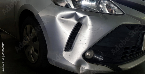Scratches or dents on gray, grey or bronze car after accident. Damaged on injured on front bumper.