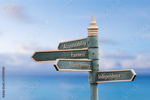 accountability fairness transparency independence four word quote written on fancy steel signpost outdoors by the sea. Soft Blue ocean bokeh background.