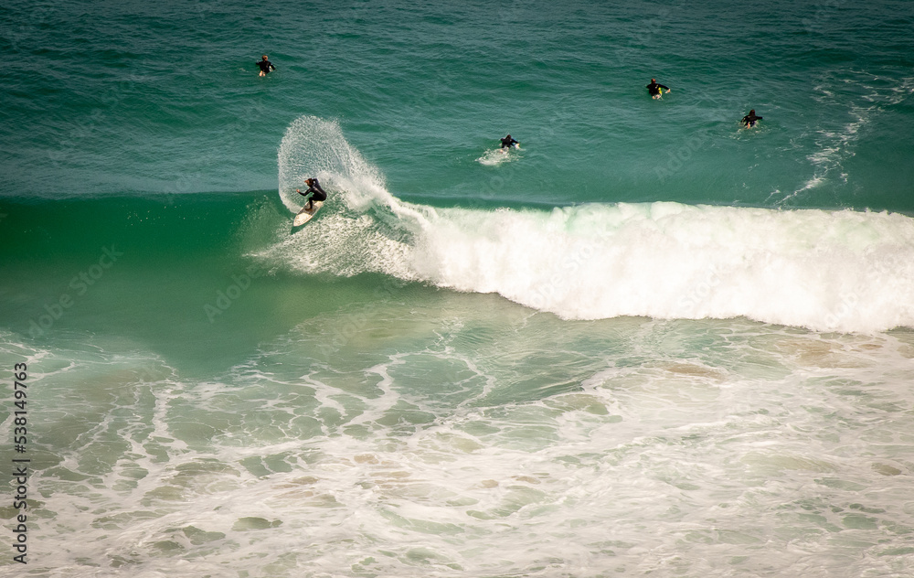 Surfer at crest of turquoise wave far shot