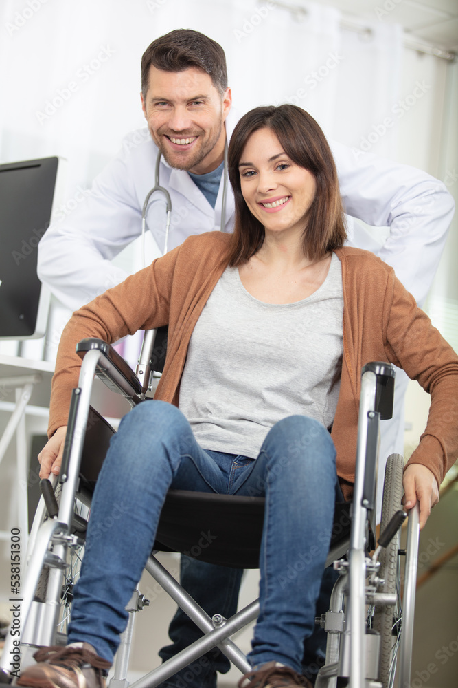 male doctor pushing attractive woman in a wheelchair male doctor pushing attractive woman in a wheelchair