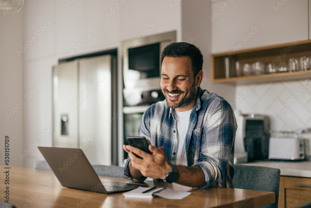 Smiling businessman using a phone while working at home. Smiling businessman using a phone while working at home.