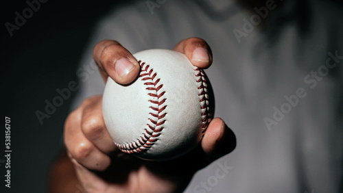 Selective focus of man holding baseball ball isolated on black background.