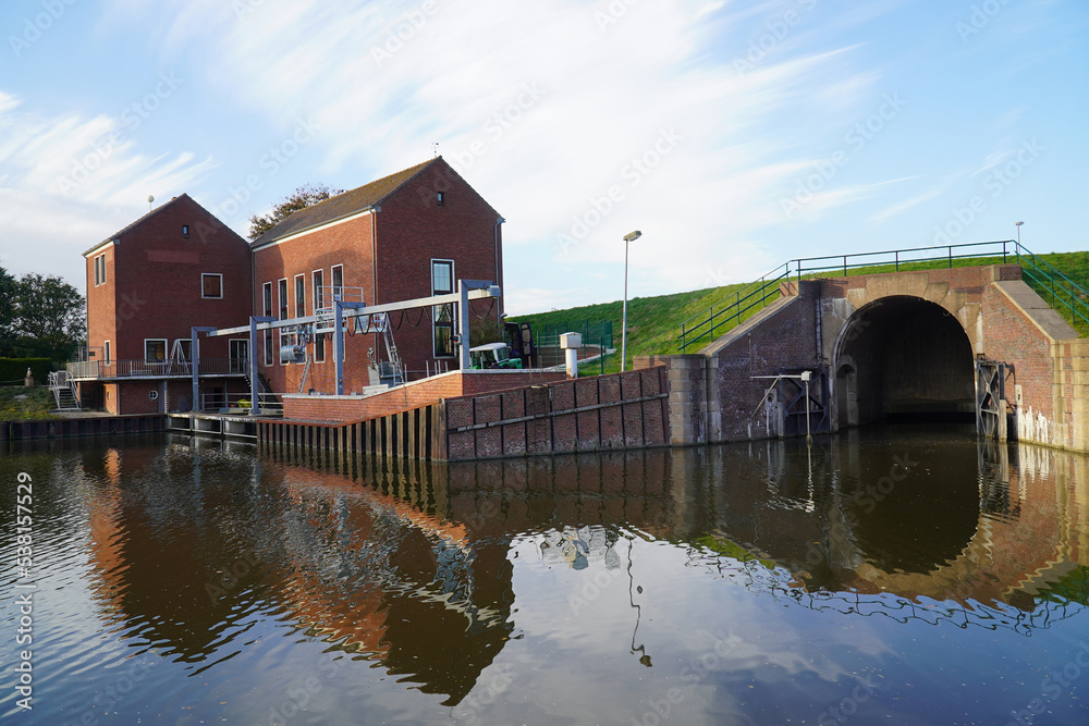 Fototapeta premium Coastal pumping station near the small harbor at the Ley Bay in Greetsiel, western East Frisia, Lower Saxony, Germany, Europe.