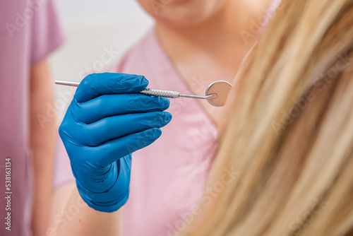 The  dentist using mirror to look at the client s teeth