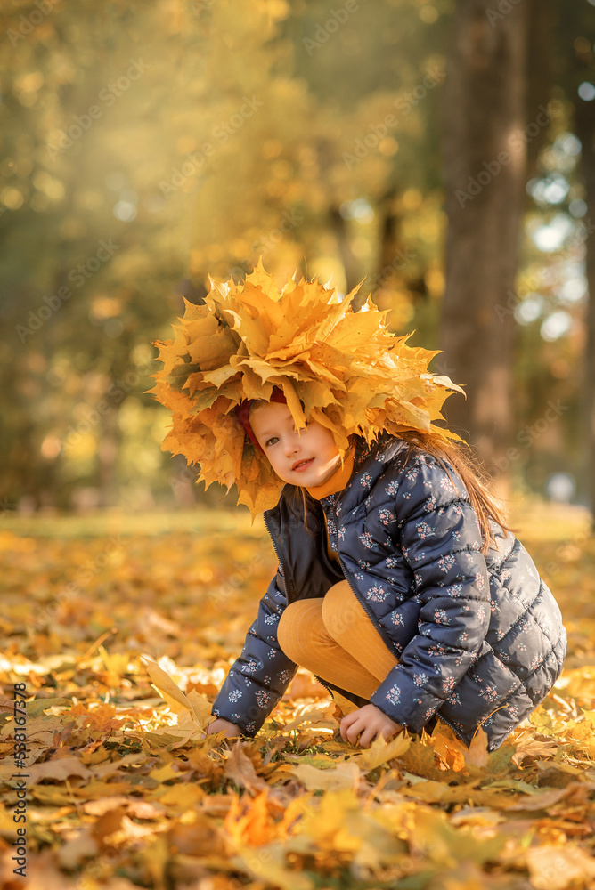 little girl is playing with leaves in the park 