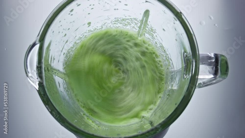 Closeup green vegetables mix in blender top view. Healthy vegan smoothie. photo