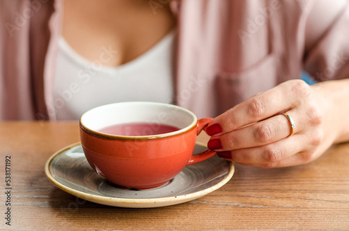 Young woman holding a cup of red tea in a cafe. In the background is her beautiful cleavage