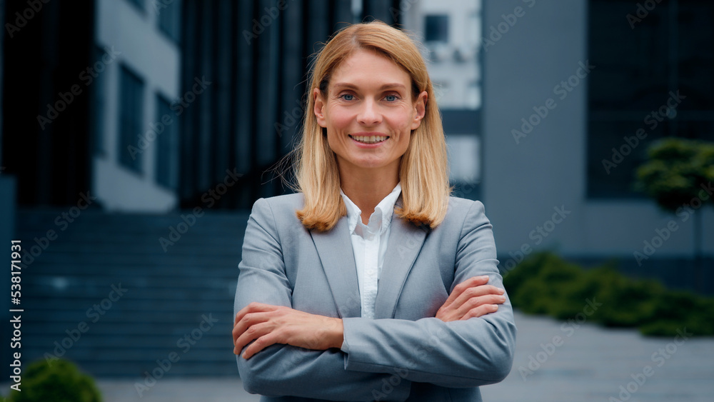 Close-up confident successful young businesswoman in formal suit posing with crossed arms outdoors smiling ambitious independent woman leader professional manager looking at camera standing on street Close-up confident successful young businesswoman in formal suit posing with crossed arms outdoors smiling ambitious independent woman leader professional manager looking at camera standing on street