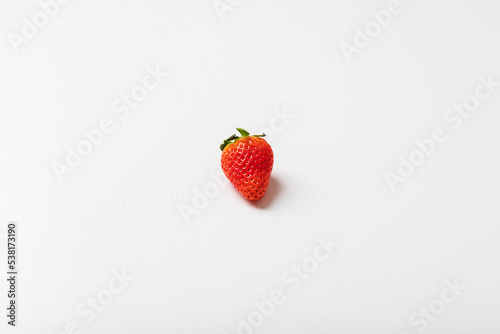 Red strawberry with a green stem is isolated on a white background.