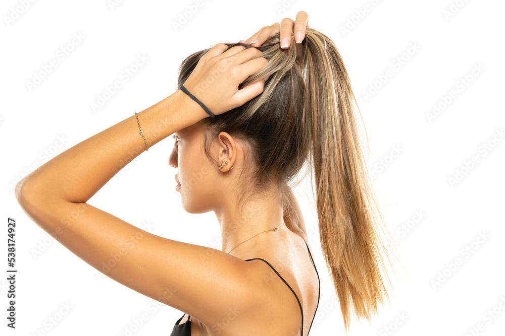 Young beautiful woman tying her hair in a ponytail on a white background Young beautiful woman tying her hair in a ponytail on a white background