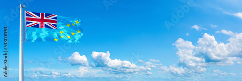 Tuvalu flag waving on a blue sky in beautiful clouds - Horizontal banner photo