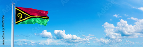 Vanuatu flag waving on a blue sky in beautiful clouds - Horizontal banner photo