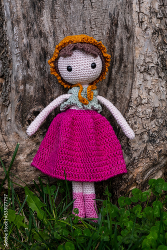 Knitted toy baby lean on the tree. Creative hobby, amigurumi.