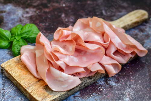 Slices Of  Traditional Italian antipasti mortadella Bolognese  on a wooden  cutting board. photo