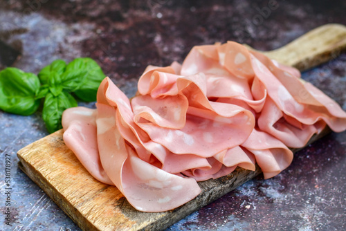 Slices Of  Traditional Italian antipasti mortadella Bolognese  on a wooden  cutting board. photo