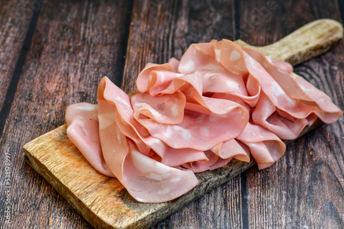 Slices Of  Traditional Italian antipasti mortadella Bolognese  on a wooden  cutting board