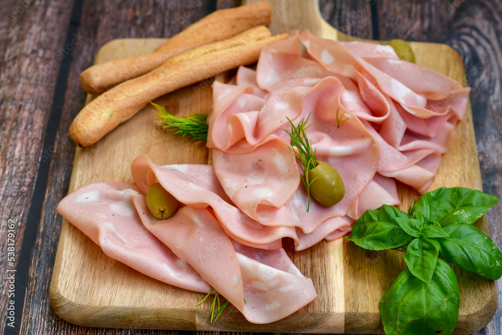 Slices Of Traditional Italian antipasti mortadella Bolognese on a wooden cutting board Stock