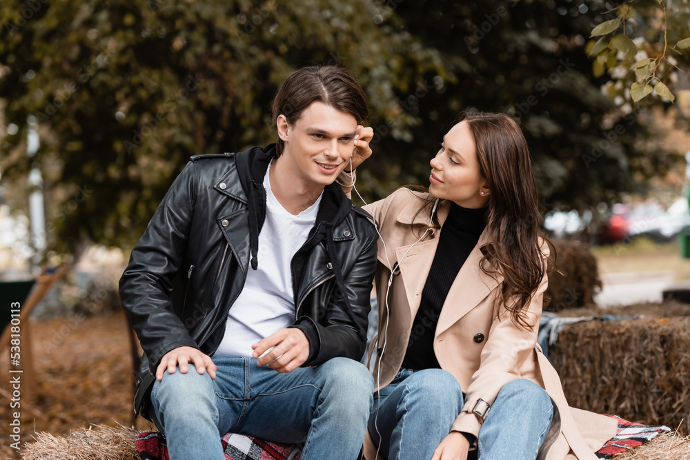 smiling young woman adjusting wired earphone in ear of happy boyfriend. smiling young woman adjusting wired earphone in ear of happy boyfriend.