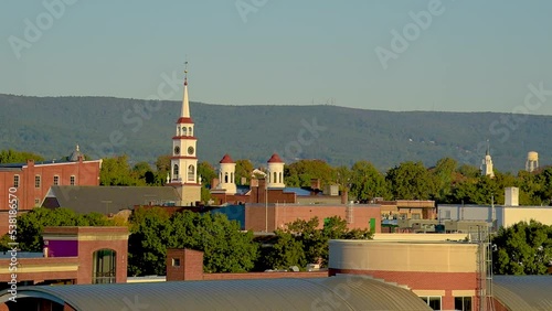 View of church spires in the city of Frederick, Maryland with trees and a hill in the background. photo