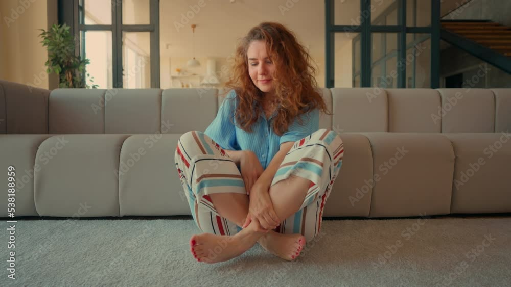 adult woman with crossed legs sitting on the floor in apartment lady with curly hair practicing meditation for concentration