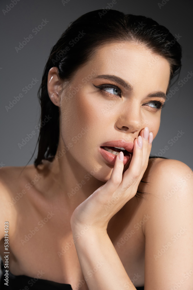 Portrait of sexy brunette woman touching lips isolated on grey. Portrait of sexy brunette woman touching lips isolated on grey.