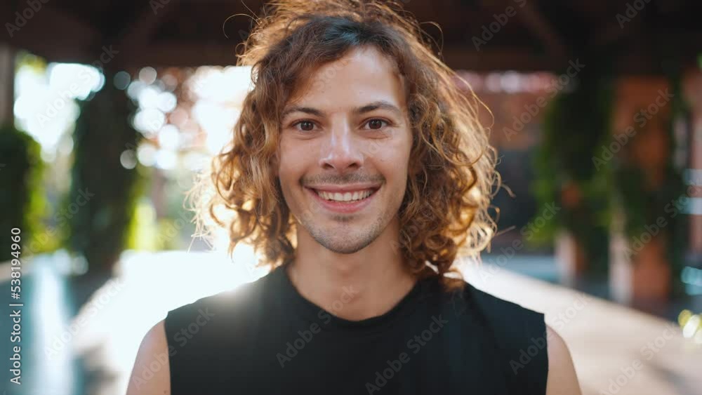 Smiling athletic man with curly hair looking at the camera on yoga mat outdoors Smiling athletic man with curly hair looking at the camera on yoga mat outdoors