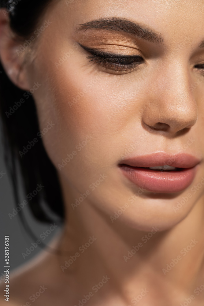Cropped view of young brunette woman with visage isolated on grey. Cropped view of young brunette woman with visage isolated on grey.