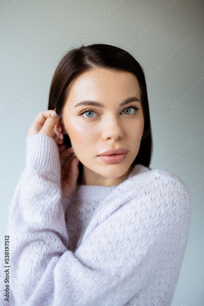 portrait of charming brunette woman in knitted sweater looking at camera isolated on grey. portrait of charming brunette woman in knitted sweater looking at camera isolated on grey.