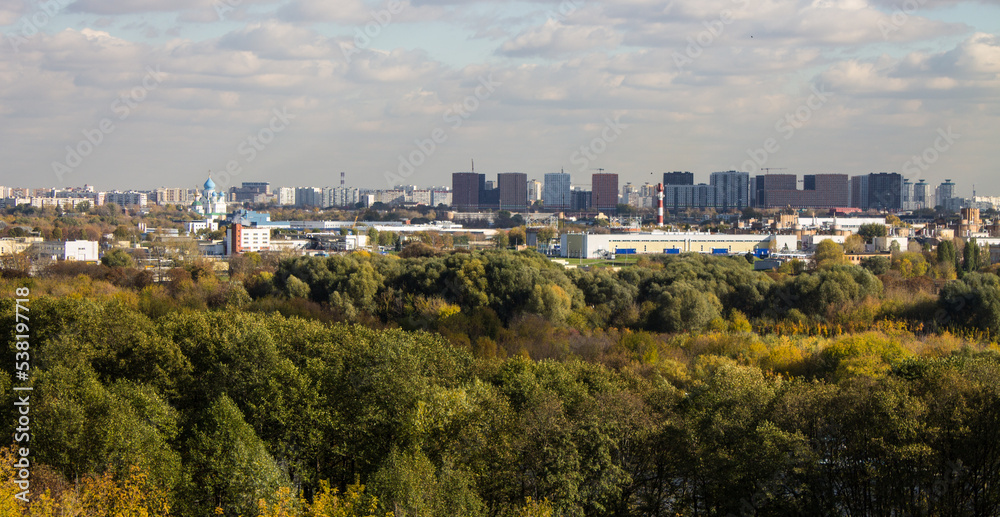 Panoramic top view of the city of Moscow with buildings among the lush foliage of autumn trees on a sunny cloudy October d