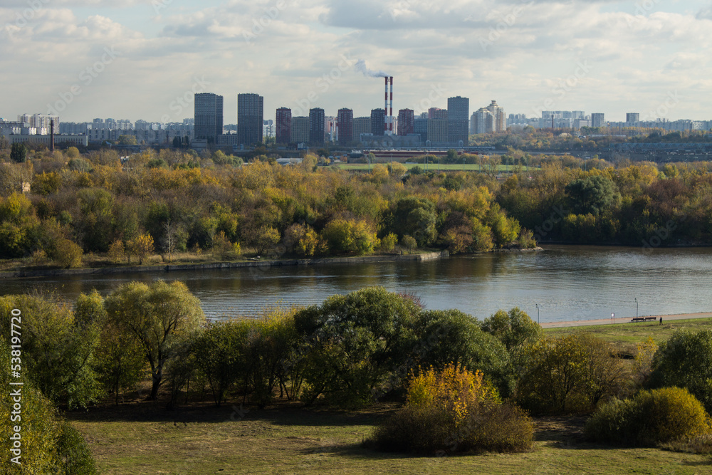Panoramic top view of the city of Moscow with buildings among the lush foliage of autumn trees and the river on a sunny cloudy October day