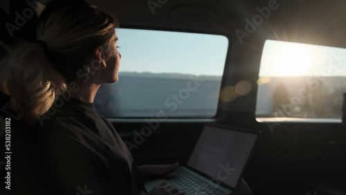 woman working from her laptop while traveling in daylight in a private vehicle,private transportation and daylight
