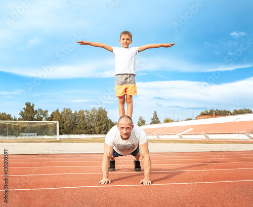 Father and son go in for sports together at the stadium on sunny day. selective focus