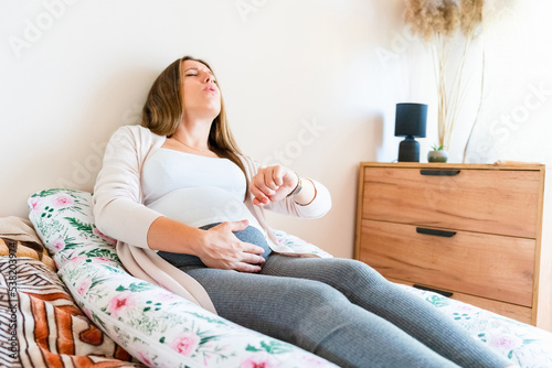 Pregnant contractions time. Pregnancy woman watching clock, holding baby belly. Childbirth time, contractions pain. Concept of pregnant, maternity, expectation for baby birth.