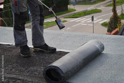 Cuadro en lienzo Roofer working on the roof. Roofing felt.