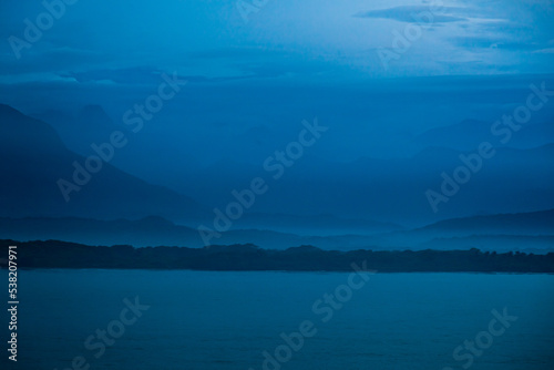 The evening coast of Colombia in the blue during the fog against the backdrop of the mountains.