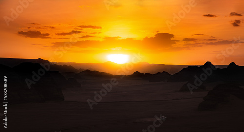 A speeding car in the desert at sunset.