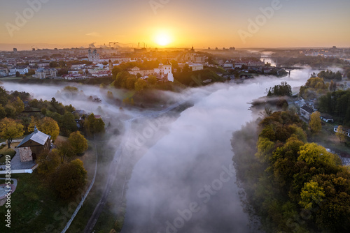 earlier foggy morning and aerial panoramic view on medieval castle and promenade overlooking the old city and historic buildings near wide river