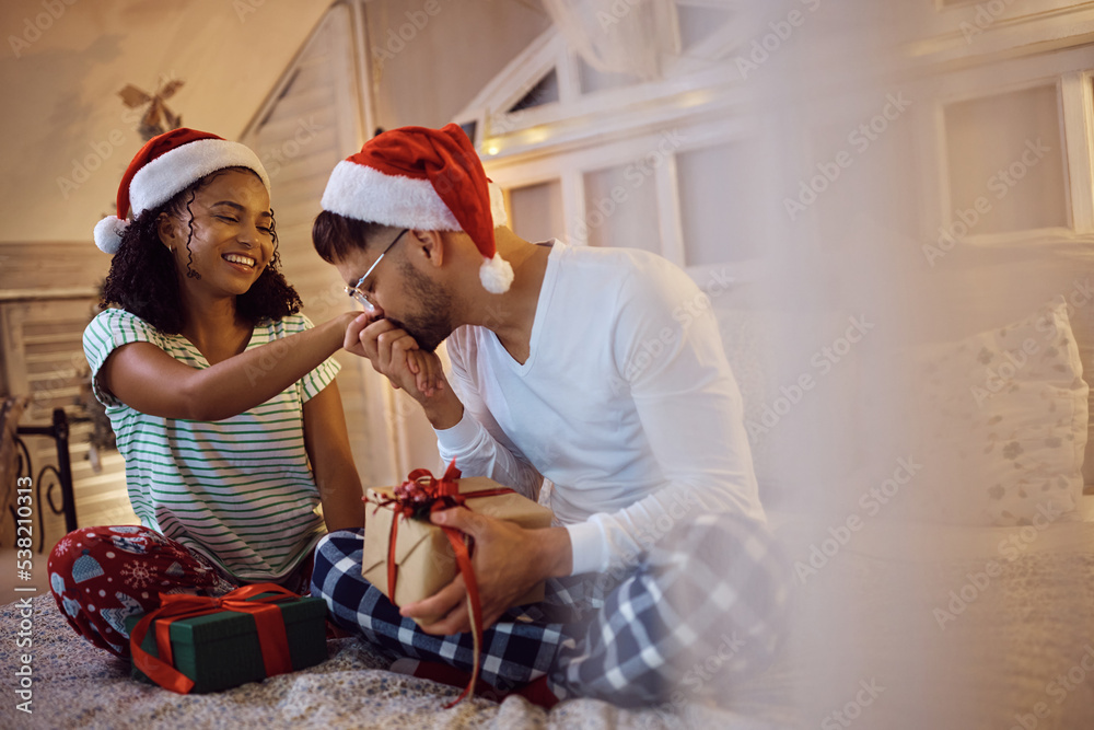 Caring man kissing girlfriend's hand after receiving Christmas present from her at home. Caring man kissing girlfriend's hand after receiving Christmas present from her at home.