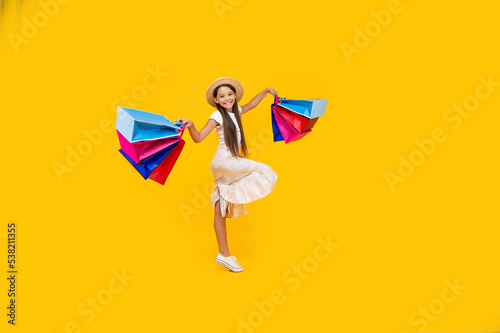 happy teen girl with shopping bags on yellow background. full length. cyber monday