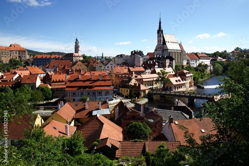 overview over Pesky Krumlov with Moldau River bridge, church and historic houses, blue sky sunny day few white clouds