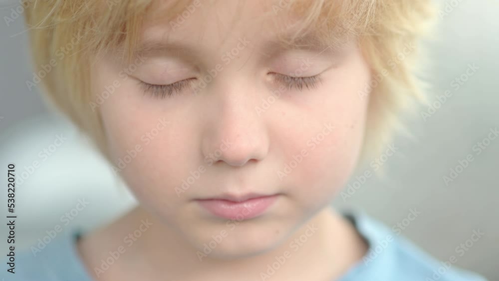 Close-up portrait of sad and thoughtful school-age child. The cute boy closed his eyes, then opened them and looks at you very seriously. Upset, offended and lonely kid Close-up portrait of sad and thoughtful school-age child. The cute boy closed his eyes, then opened them and looks at you very seriously. Upset, offended and lonely kid