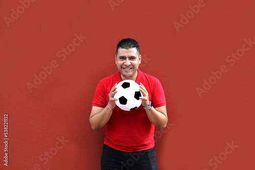 Latino adult man plays with a soccer ball very excited that he is going to see the World Cup and wants to see his team win