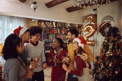 Multiracial group of happy people talk while celebrating New Year at home party.