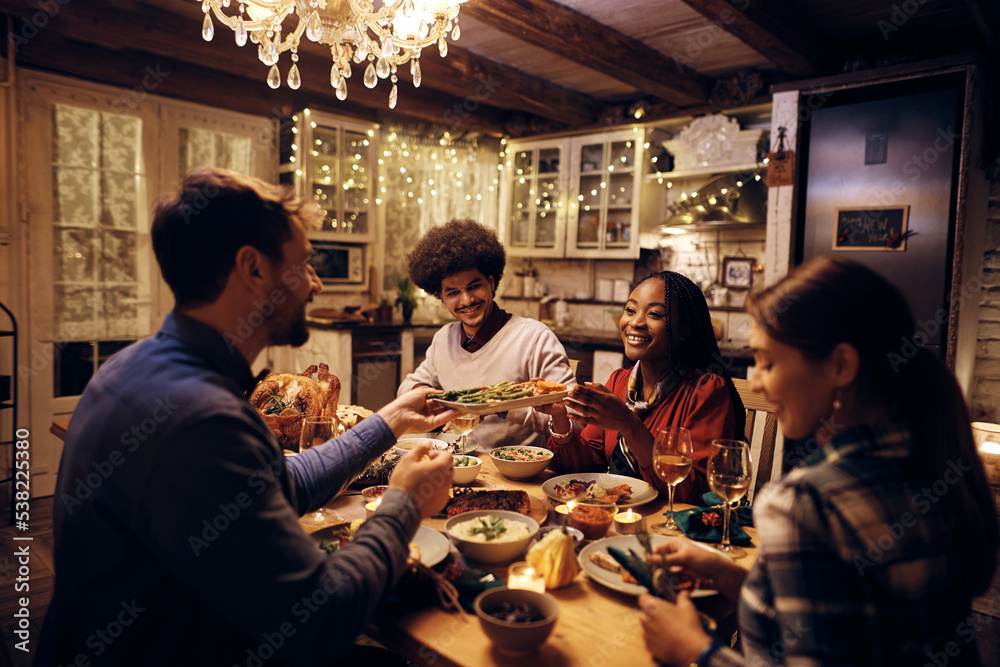Multiracial group of happy friends enjoying in Thanksgiving dinner at dining table.