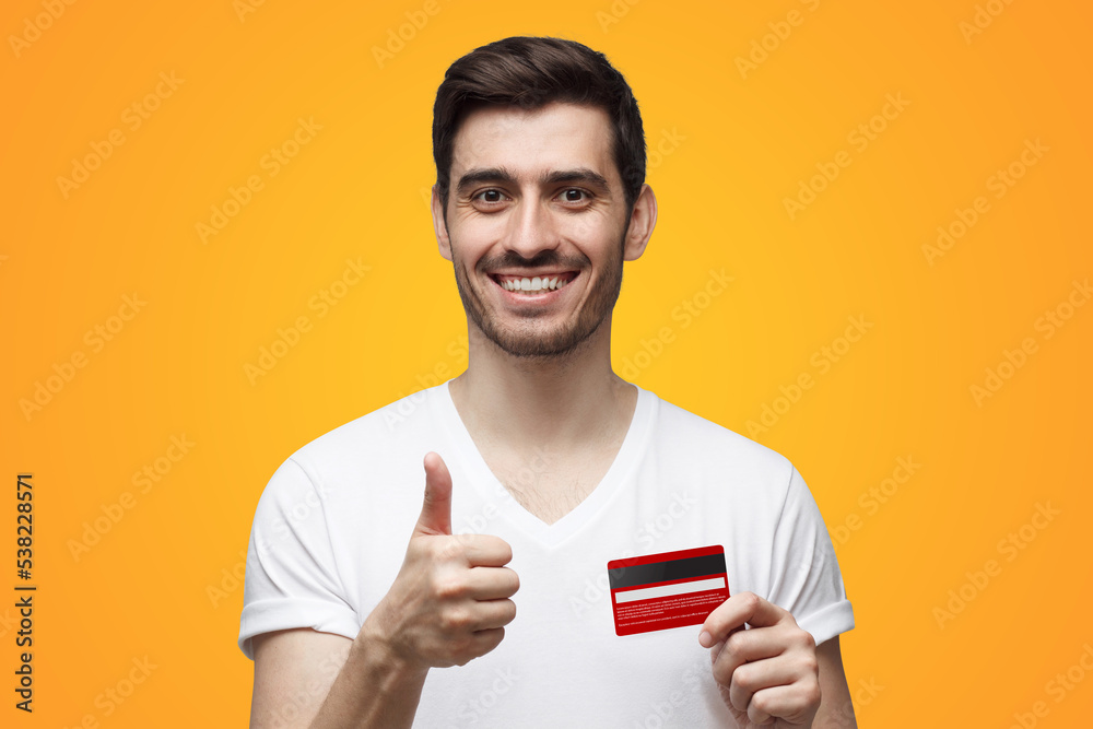 Man holding credit card, showing thumbs up gesture recommending best bank on yellow background