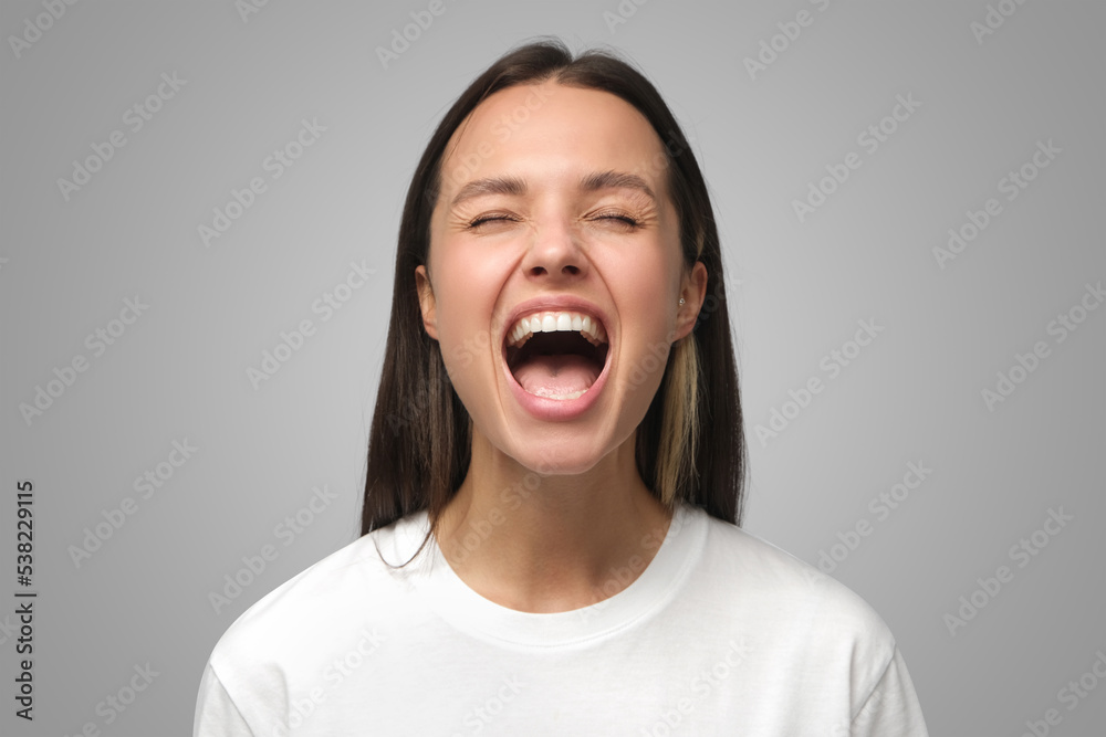 Close-up portrait of screaming with closed eyes crazy young female isolated on gray Close-up portrait of screaming with closed eyes crazy young female isolated on gray