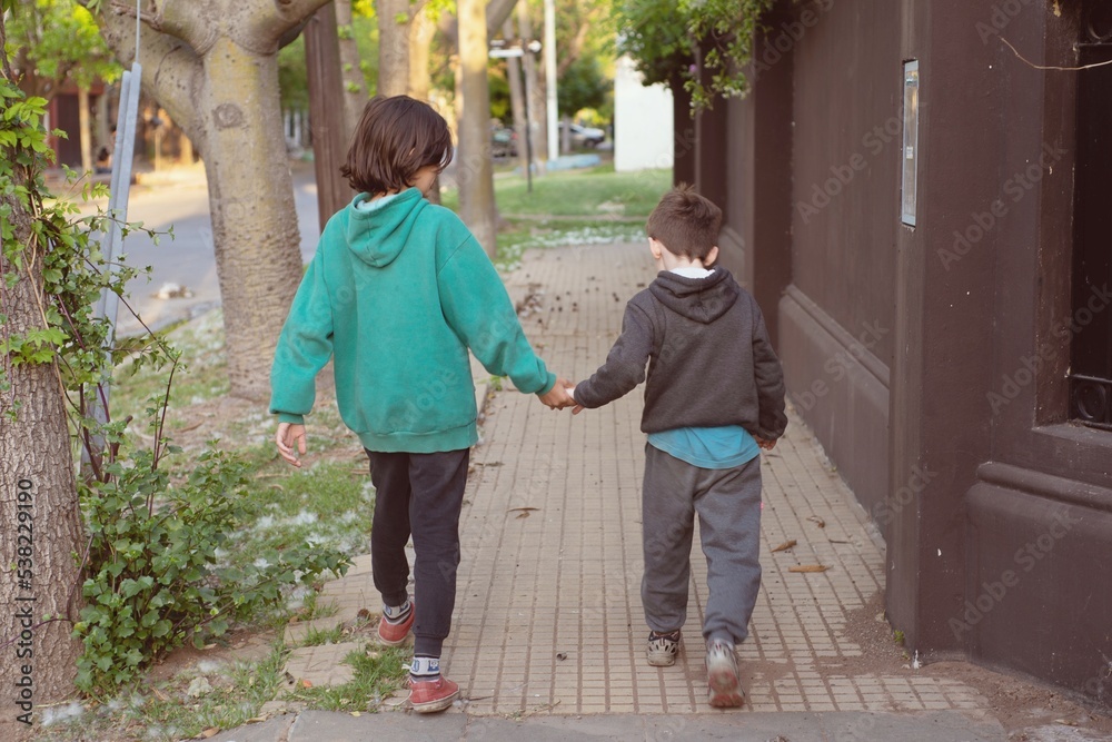 Niños caminando de la mano por la vereda