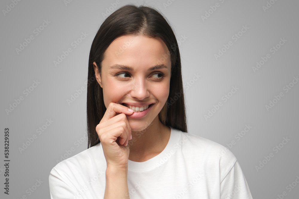 Portrait of shy beautiful young woman smiling touching lips Portrait of shy beautiful young woman smiling touching lips