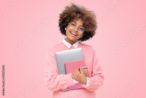 Laughing funny african american teen girl, high school student holding laptop and pink notebook