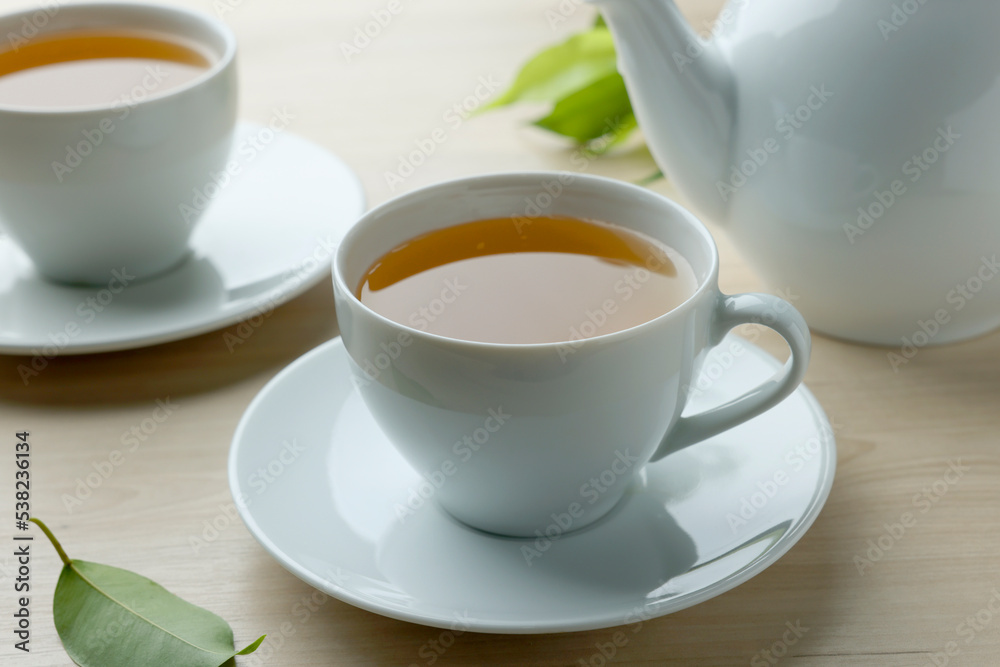 Green tea in white cups with leaves and teapot on wooden table, closeup Green tea in white cups with leaves and teapot on wooden table, closeup